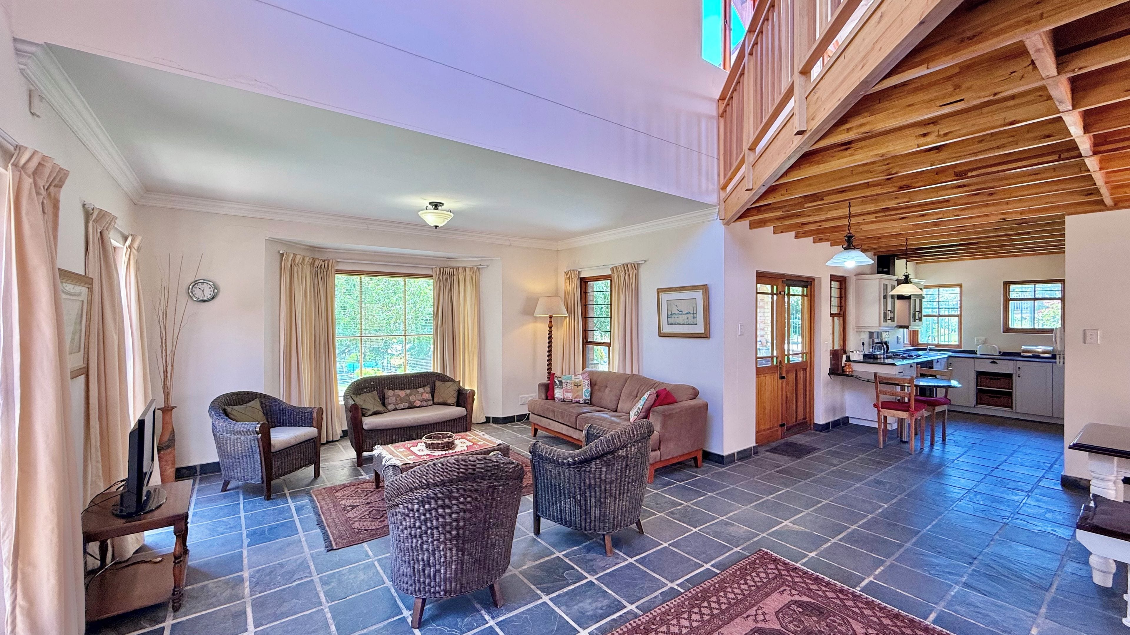 A spacious living area with a dining table, sofas, and a kitchen in the background.