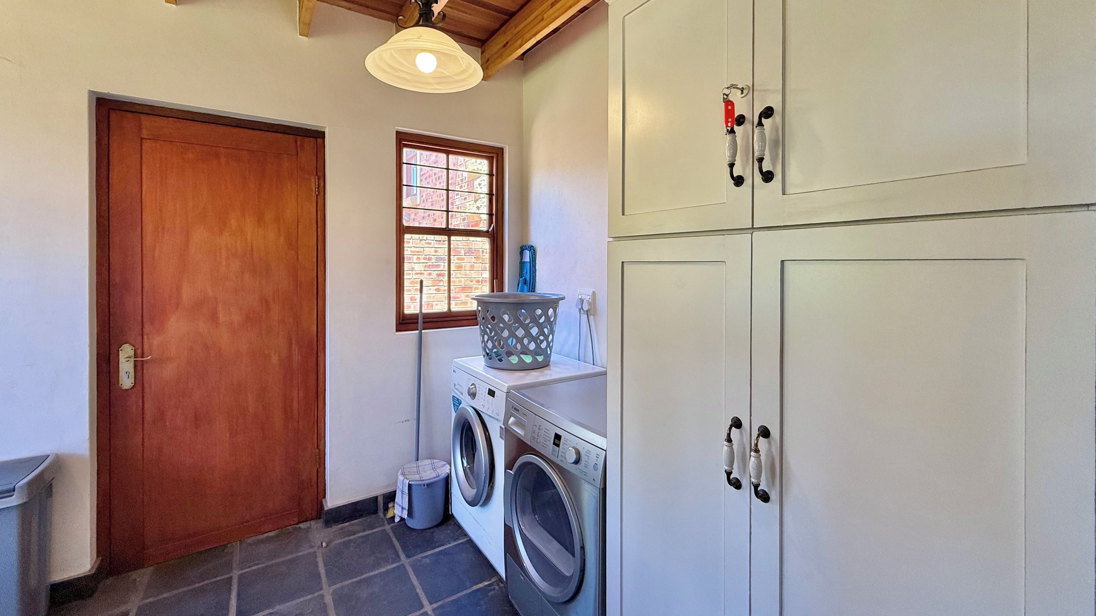 A laundry room with a washing machine, a drying rack, a basket, and a door.