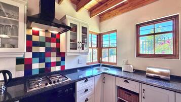 Una cocina con estufa a gas, tostadora y un salpicadero de colores.