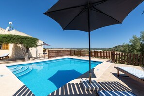 A clear blue swimming pool with a wooden deck and lounge chairs, surrounded by a wooden fence and vegetation. - Es Turo Des Bessons by Rentallorca (Petra)