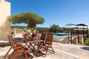 An outdoor seating area with a pool, a wooden table, and chairs. - Es Turo Des Bessons by Rentallorca (Petra)