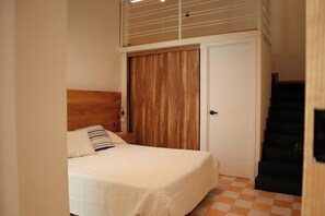 A bedroom with a bed, a wooden wardrobe, a door, and a staircase. - Gran Suite Loft Guadalajara Centro SF (Guadalajara)