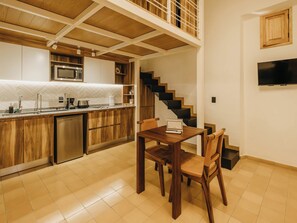 A modern kitchen with wooden cabinets, a built-in microwave, and a dining area with a table and chairs. - Loft en el Centro Histórico de GDL (Guadalajara)