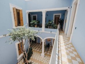 A multi-level interior with checkered flooring, white columns, and potted plants. - Alojamiento en el corazón de Guadalajara LC (Guadalajara)