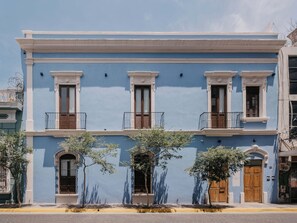 Ein zweistöckiges Gebäude mit blauer Fassade, weißem Zierrat und einem Balkon im zweiten Stock.