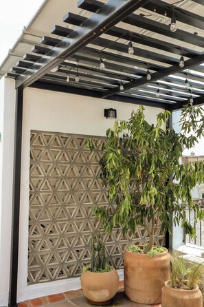 A covered outdoor area with a geometric patterned wall, potted plants, and hanging light fixtures. - Alojamiento en el corazón de Guadalajara LC (Guadalajara)
