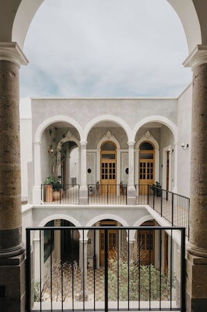 A courtyard with a central open space, surrounded by white columns and arches, with a balcony overlooking the area. - Bonito Mini loft Zona Centro SF (Guadalajara)