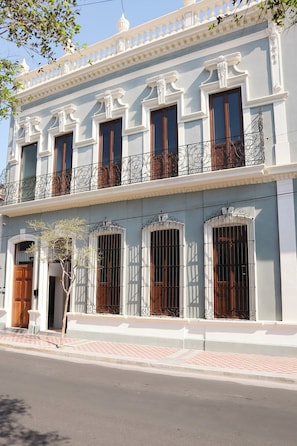 A two-story building with a balcony, a wooden door, and barred windows. - Bonito Mini loft Zona Centro SF (Guadalajara)