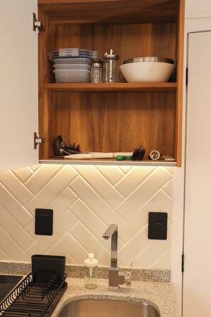 A kitchen with a wooden cabinet, a stainless steel sink, and a herringbone tile backsplash. - Bonito Mini loft Zona Centro SF (Guadalajara)