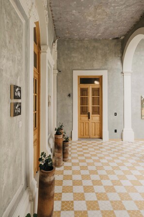 A hallway with a checkered floor, a wooden door, and potted plants. - Bonito Mini loft Zona Centro SF (Guadalajara)