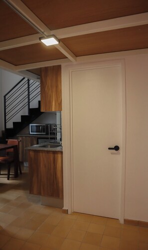 A kitchen with a microwave, a wooden cabinet, and a door with a handle. - Loft en el centro de Guadalajara LC (Guadalajara)