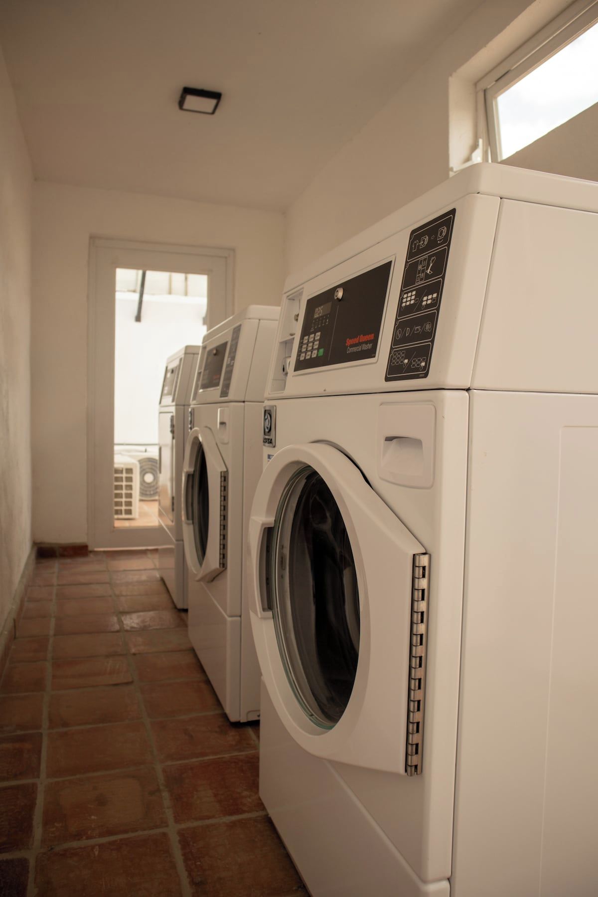 A laundry room with three front-loading washing machines and a dryer.