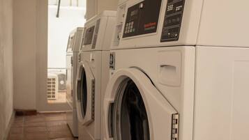A laundry room with three front-loading washing machines and a dryer.