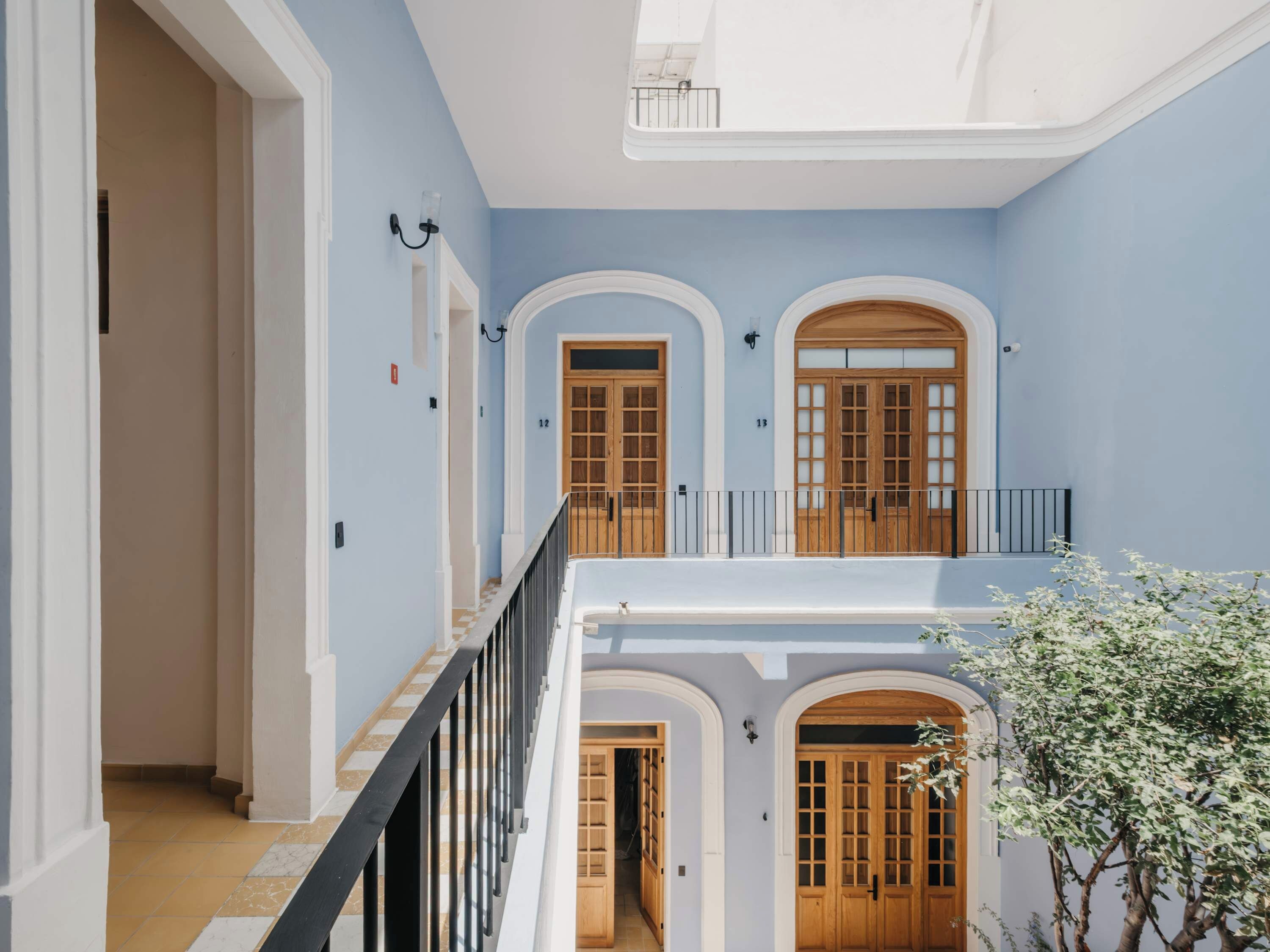 Un intérieur à plusieurs niveaux, avec un escalier, des portes en bois et un balcon.