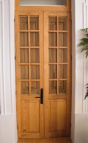 A wooden double door with a modern handle and glass panels. - Alojamiento en casa histórica del centro de GDL LC (Guadalajara)