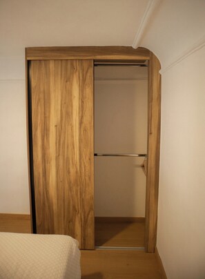 A room with a wooden wardrobe, a bed with a quilted cover, and a white wall. - Alojamiento en casa histórica del centro de GDL LC (Guadalajara)