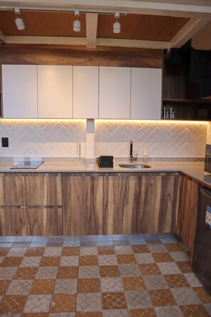 A kitchen with wooden cabinets, a herringbone-patterned backsplash, a granite countertop, and a tiled floor. - Suite Loft Guadalajara Centro SF (Guadalajara)