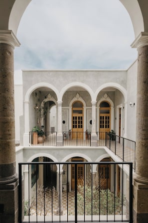 A courtyard with a central open area, surrounded by arches and columns, with a staircase leading to an upper level. - Suite Loft Guadalajara Centro SF (Guadalajara)