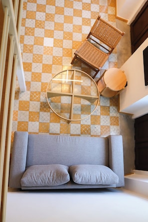 A checkered floor, a wicker chair, a round table, and a grey sofa with cushions. - Suite Loft Guadalajara Centro SF (Guadalajara)