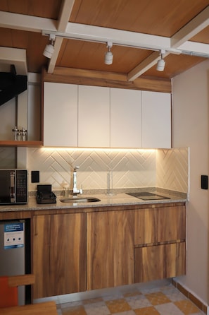 Cozinha moderna com armários de madeira, bancada de granito e micro-ondas embutido.