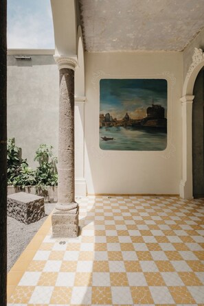 A room with a checkered floor, a large painting of a cityscape, and a column. - Loft Estandar en Casona Restaurada GDL SF (Guadalajara)