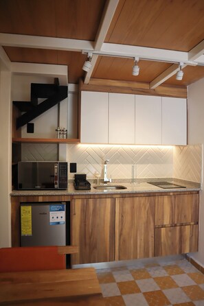A modern kitchen with wooden cabinets, a microwave, a sink, and a herringbone-patterned backsplash. - Loft Estandar en Casona Restaurada GDL SF (Guadalajara)