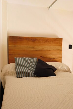A bed with a wooden headboard, a striped pillow, and a black pillow. - Loft Estandar en Casona Restaurada GDL SF (Guadalajara)