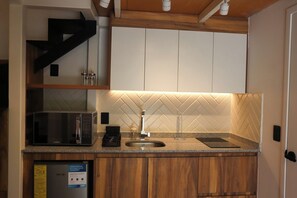A kitchen with a microwave, sink, and wooden cabinets. - Loft Estandar en Casona Restaurada GDL SF (Guadalajara)