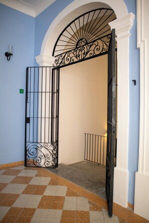 A hallway with a decorative metal gate, a tiled floor, and a blue wall. - Loft histórico en el corazón de GDL LC (Guadalajara)
