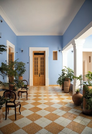A hallway with a checkered floor, wooden doors, and potted plants. - Bonito mini loft en el corazón de Guadalajara LC (Guadalajara)