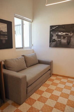 A room with a sofa, a window, a checkered floor, and two framed pictures on the wall. - Amplio loft Casa Histórica en Zona Centro SF (Guadalajara)