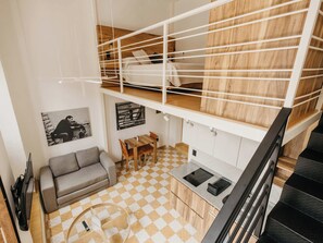A compact living space with a loft bedroom, a kitchenette, a sofa, and a dining area. - Amplio loft Casa Histórica en Zona Centro SF (Guadalajara)