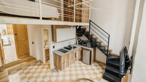 A modern kitchen with a built-in stove, a microwave, and a sink. There is a staircase leading to an upper level. - Amplio loft Casa Histórica en Zona Centro SF (Guadalajara)