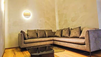 Un salón en esquina con sofá seccional, una mesa de centro y un aplique de pared.