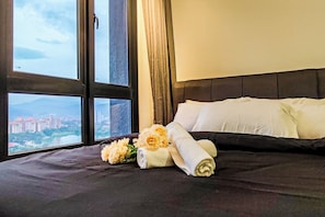 Ett hotellrum med en säng, ett fönster med utsikt över staden och en bukett blommor.