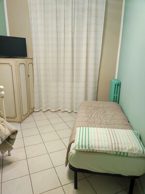 Ein Schlafzimmer mit einem Bett, einem Schrank, einem Heizkörper und einem Fernseher auf einem Tisch.