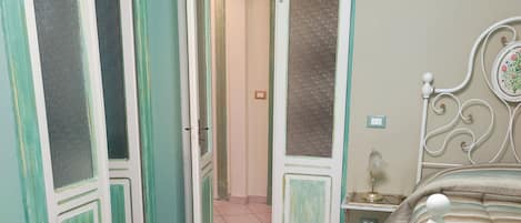 A bedroom with two beds, a tiled floor, and a door leading to another room.