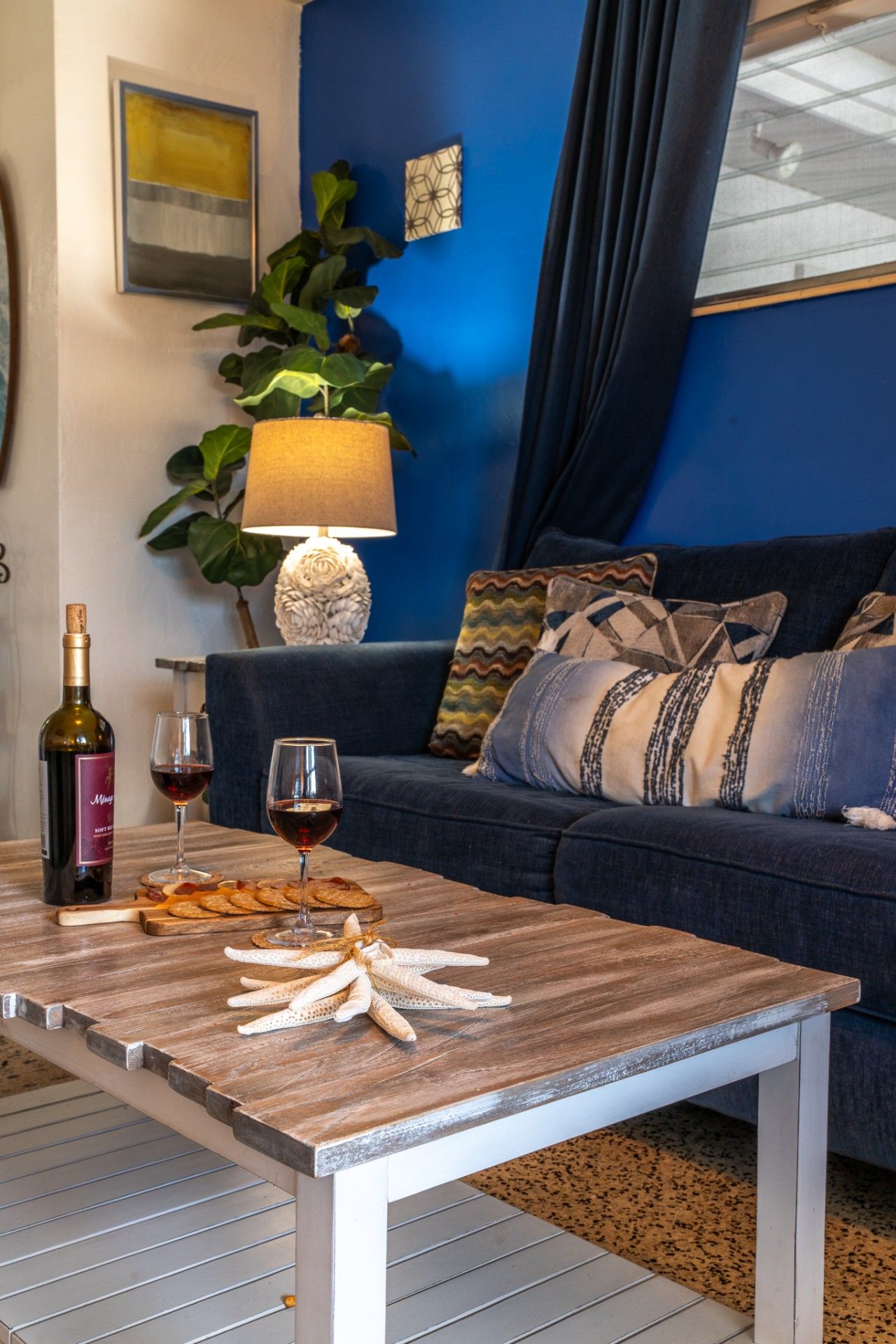 A cozy living room with a blue wall, a wooden coffee table, a sofa, and a lamp.