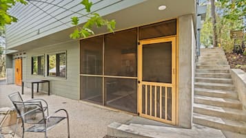 Un bâtiment doté d’un espace extérieur abrité avec des sièges, d’une porte-fenêtre coulissante et d’un escalier en béton.