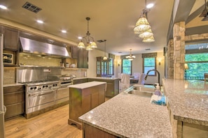 A modern kitchen with granite countertops, stainless steel appliances, and pendant lighting. - Dragon Castle: Secret Arcade, Hot Tub, Sleeps 22 (Camdenton)