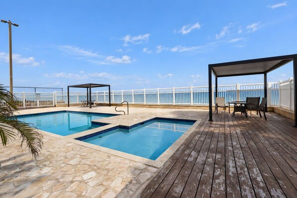 Ein Pool auf dem Dach mit zwei Bereichen, einer Holzterrasse und einem weißen Zaun.
