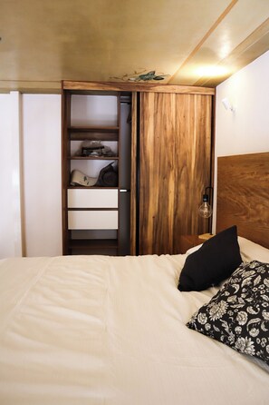 A bedroom with a bed, a wooden wardrobe, and a nightstand with a lamp. - SF Tipo A (6, 7, 14, 15) · Loft en Casona Histórica Centro GDL SF (Guadalajara)