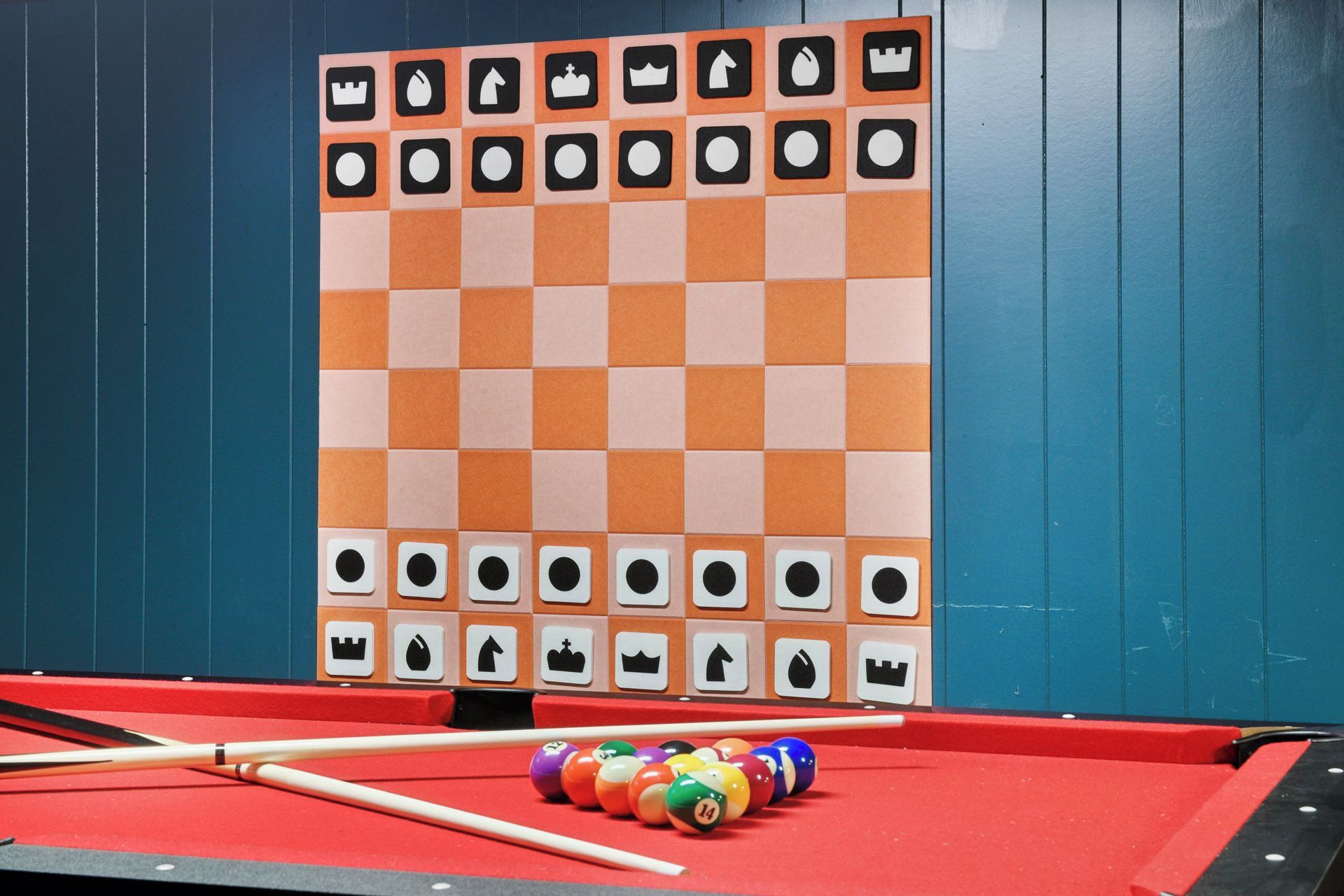A pool table with a checkered tablecloth, pool cues, and colorful balls.
