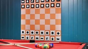 A pool table with a checkered tablecloth, pool cues, and colorful balls.