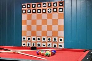 A pool table with a checkered tablecloth, pool cues, and colorful balls.