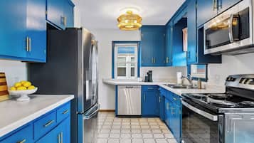 Une cuisine moderne avec des armoires bleues, des appareils en acier inoxydable et un sol carrelé à motifs hexagonaux.