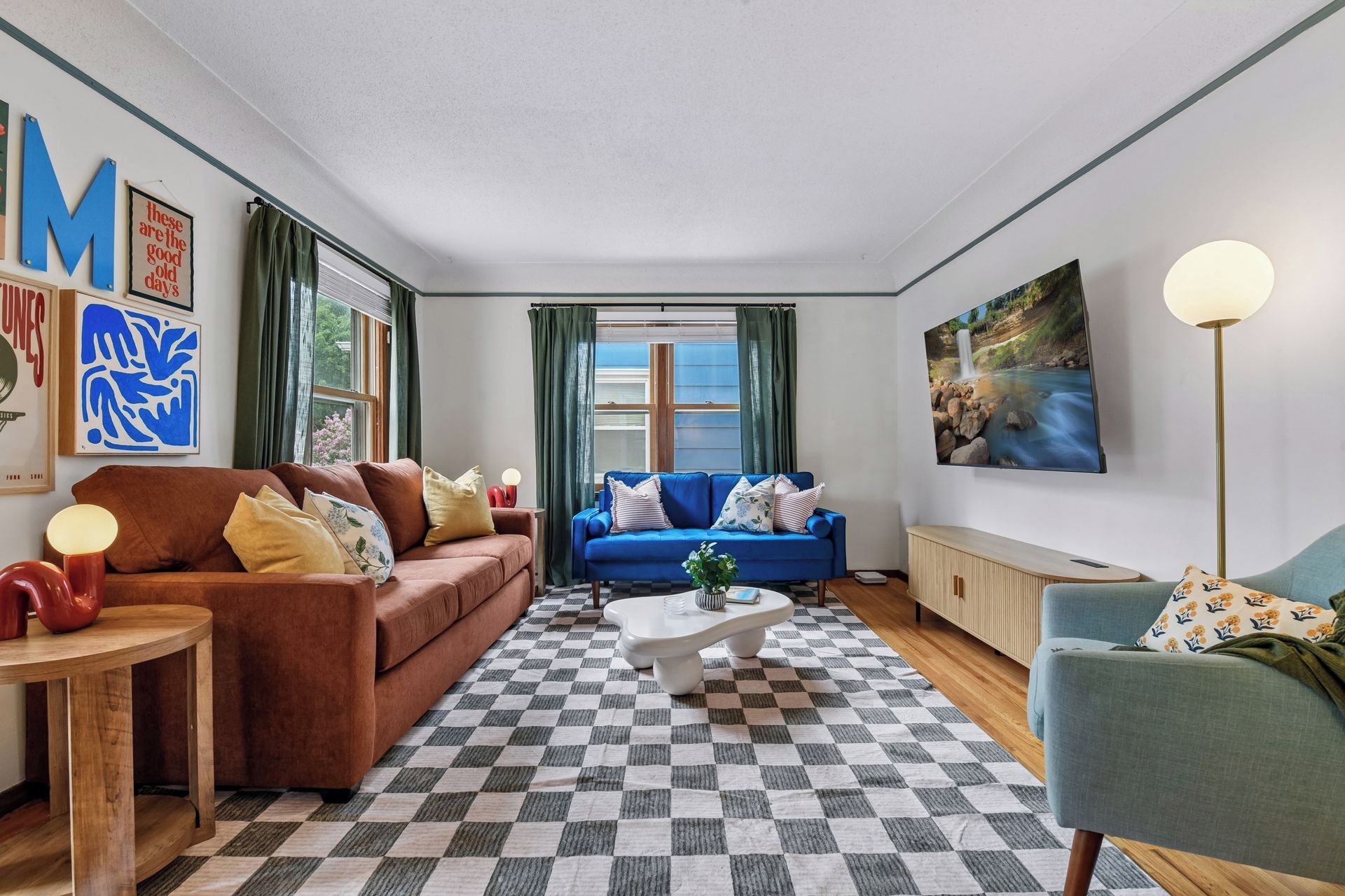 A living room with a checkered floor, two sofas, a coffee table, and a television mounted on the wall.