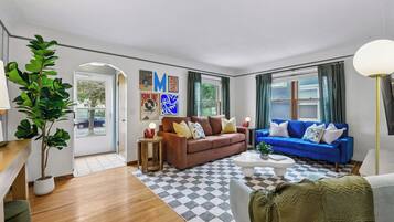 A living room with a brown sofa, a blue sofa, a coffee table, and a lamp.