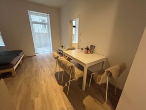 A small, well-lit room with a bed, a white table with chairs, a window, and a door. - Top 1 - 2 Minutes to imperial Park, close to center, good public transportation (Wien)