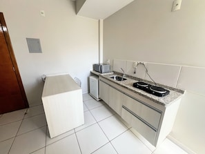 A modern kitchen with a built-in microwave, a sink, and a compact refrigerator. - CRCN - Golden Dolphin Supreme (Caldas Novas)